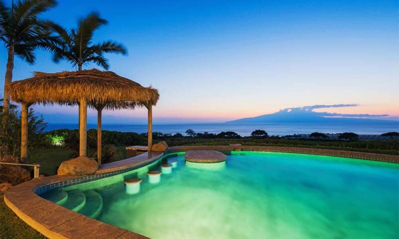 Pool overlooking ocean with sunset in background.