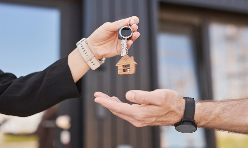 Woman handing house key to a man.