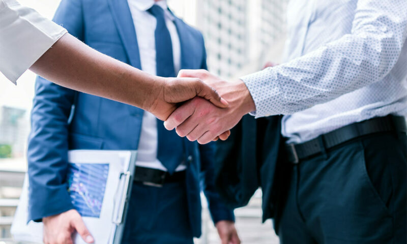 Lawyers shake hands on a city street.