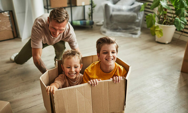 Dad pushes boys around in cardboard boxes.