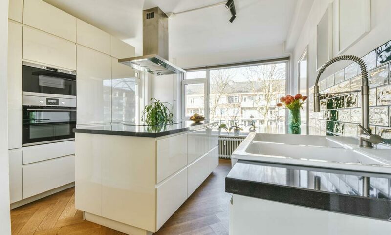 White kitchen with island and large window.