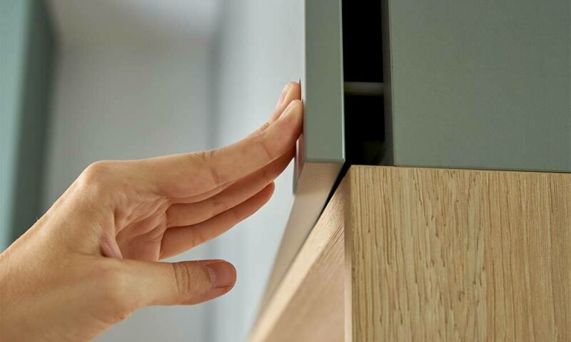 Hand pushing green cabinet door shut