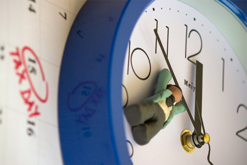 clay figurine holding onto a clock hand