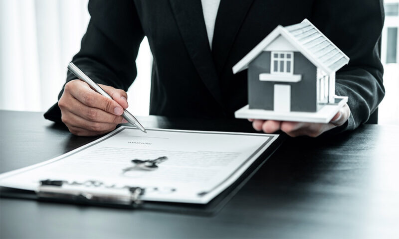 Man going over paperwork holding a model of a house.