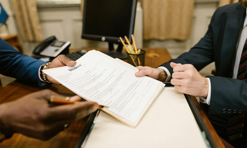 Lawyer handing man a stack of divorce papers in his office