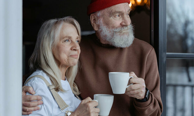 Elderly couple on their porch with coffee mugs