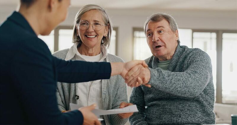 financial advisor shaking hands with senior couple