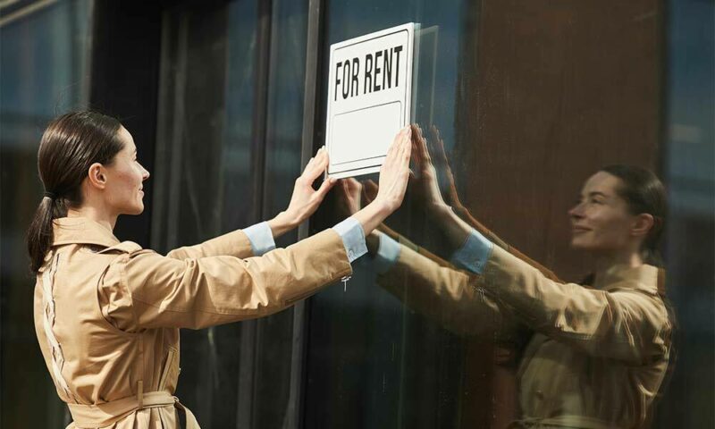 Woman puts a "For Rent" sign on window