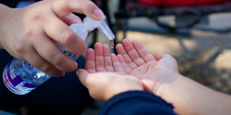 Kids using hand sanitizer together.