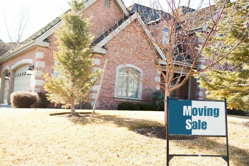 house with a moving sale sign in the front yard