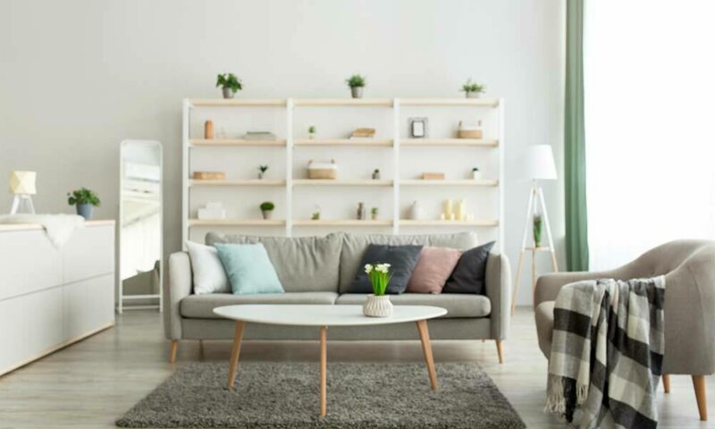 Living room with white walls and furniture and brightly colored décor on shelves