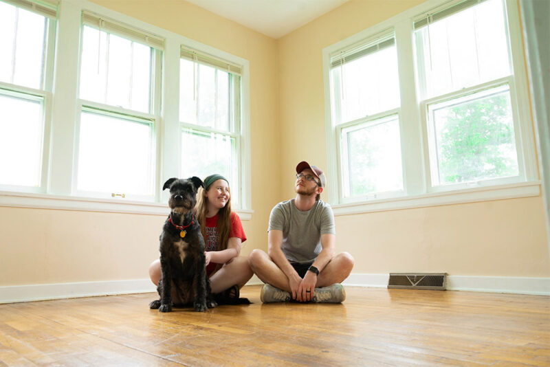 new homeowner couple in their empty living room with their dog