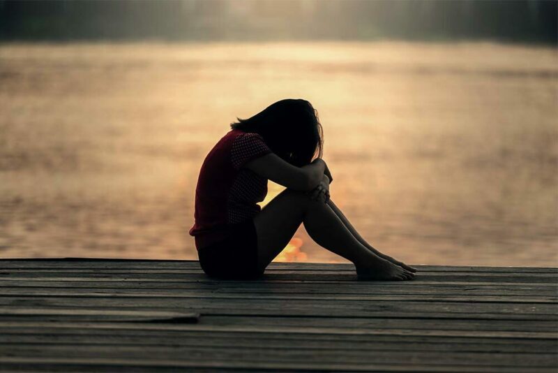 Sad girl sitting on a dock