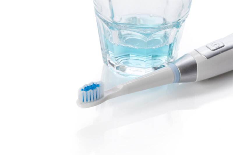 electronic toothbrush next to cup of water