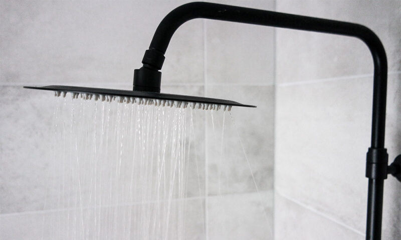 Black modern style shower head running.