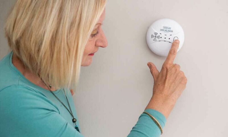 woman checking smoke detector