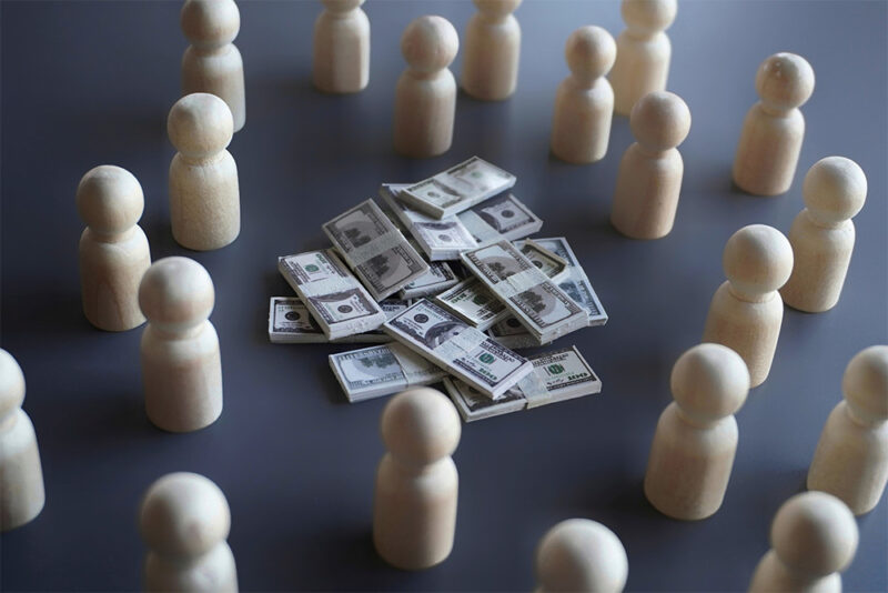 Group of wooden dolls around a pile of cash