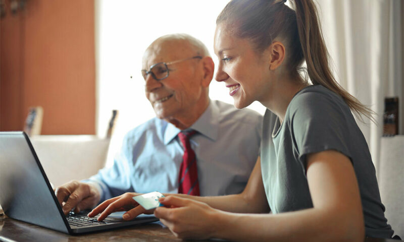 Young woman helping and elderly man with a laptop